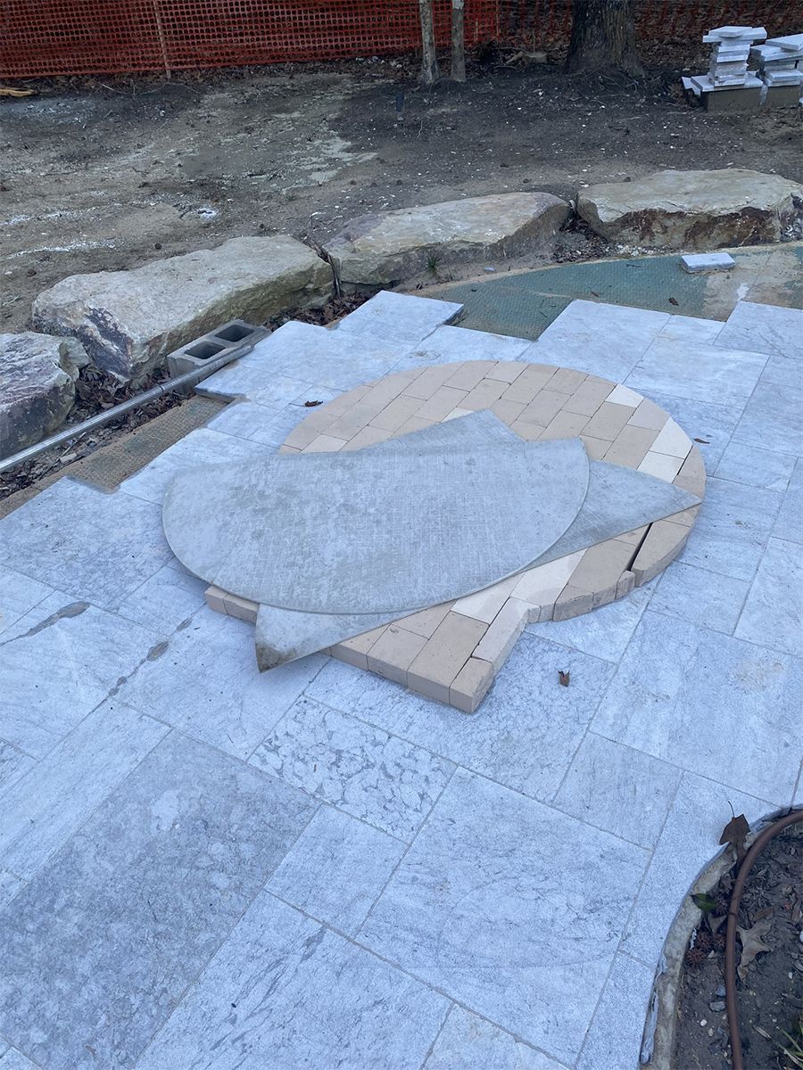 Construction of a patio with stone pavers, a circular design element in progress.