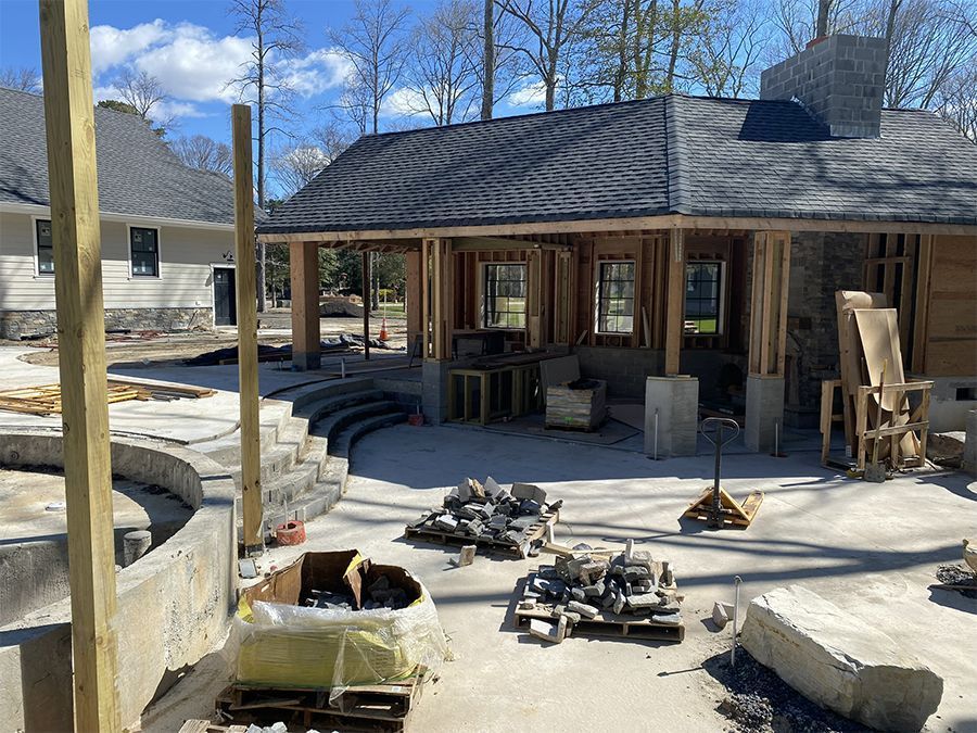 Construction site with wooden framing, stone, and unfinished structures; light sky.