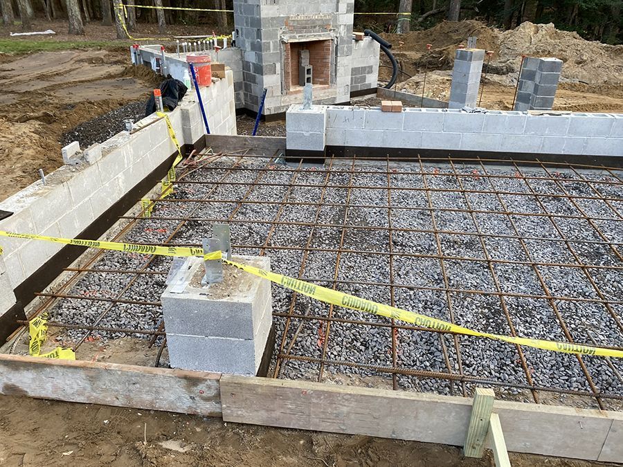 Construction site with concrete foundation and cinder block walls; rebar grid visible.