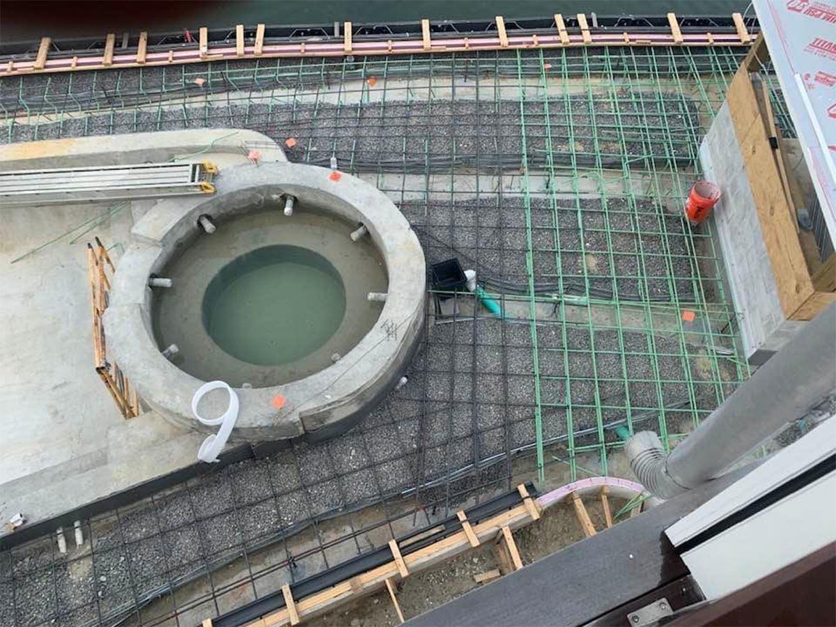 Construction site: concrete structure with pool, rebar, and wooden forms.