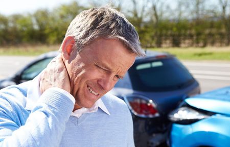 A man is holding his neck in pain after a car accident.