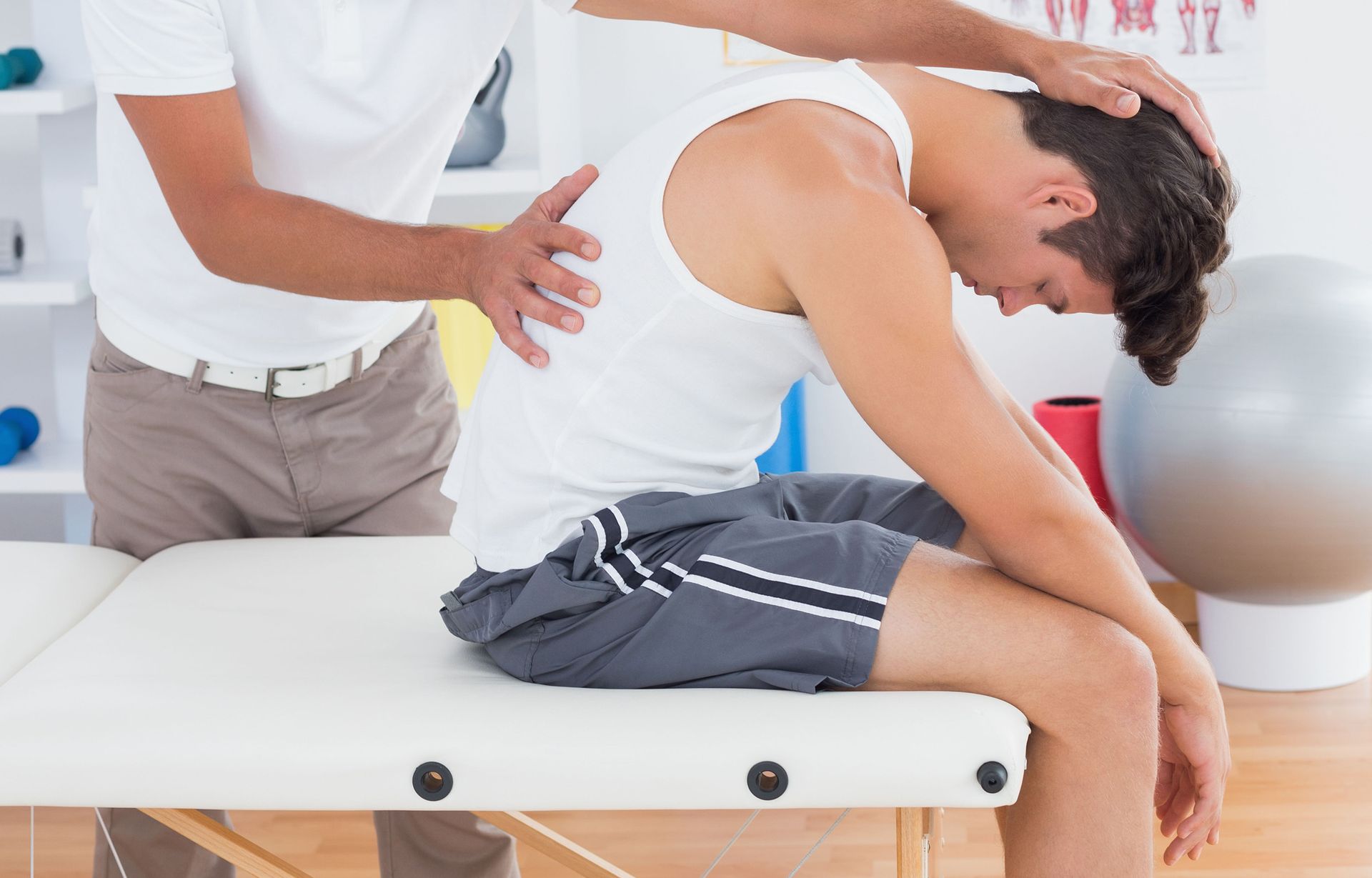 A man is stretching his back while sitting on a table.