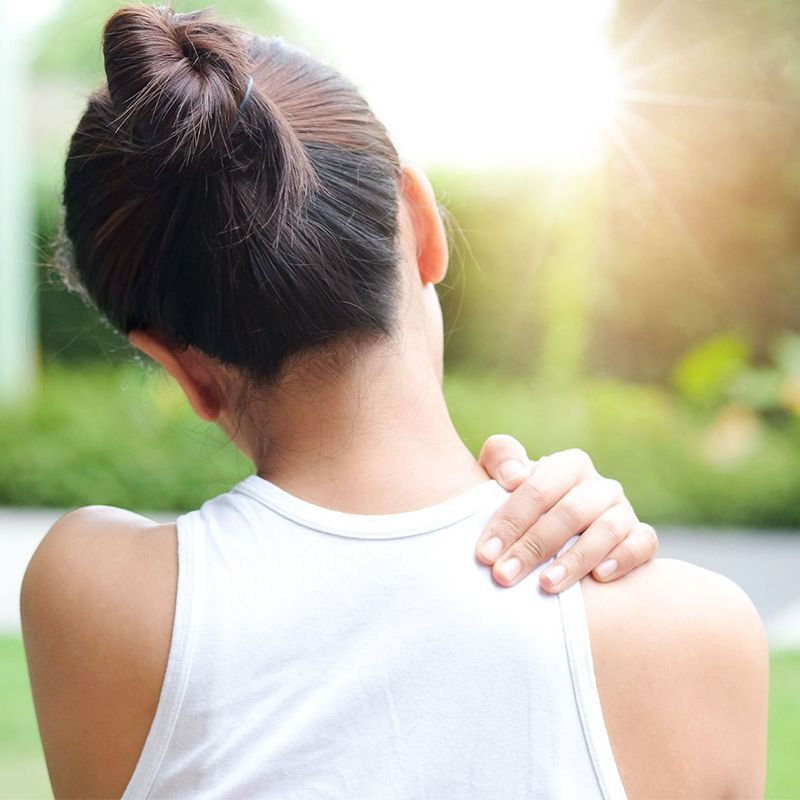 A woman is holding her shoulder in pain.