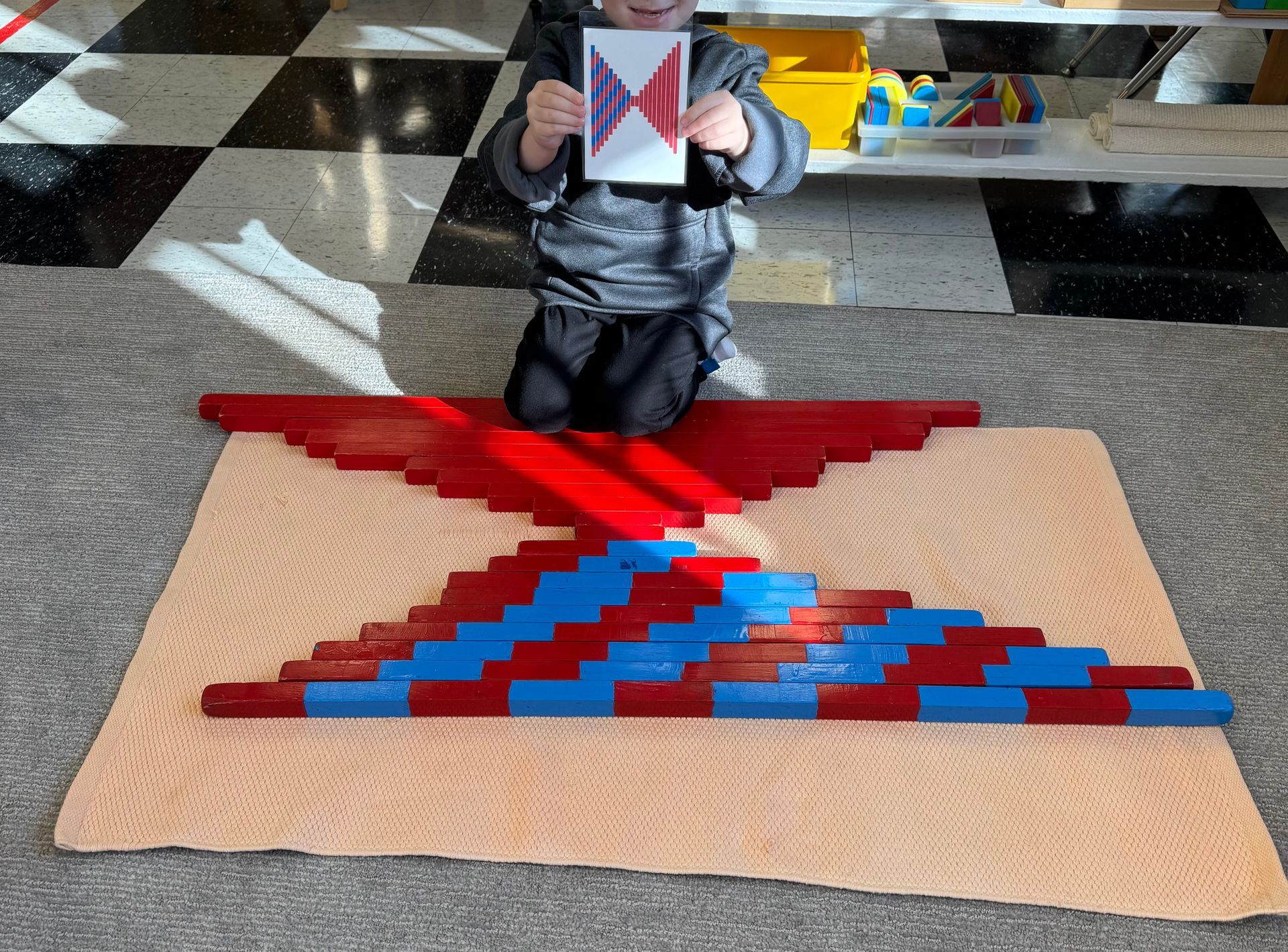 A child is sitting on the floor holding a card with a fish on it.