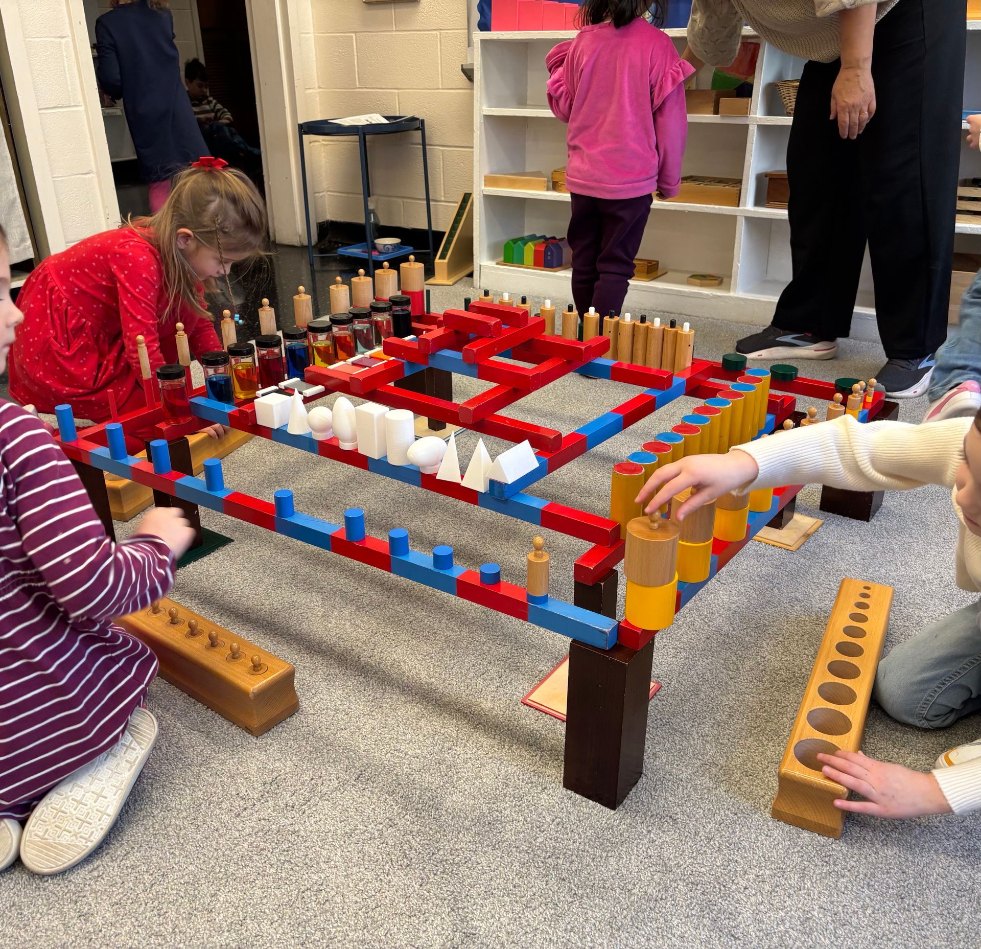 children playing with blocks of various sizes and matching them to a square block puzzle