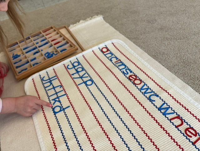 A child is playing with a mat that has the alphabet on it