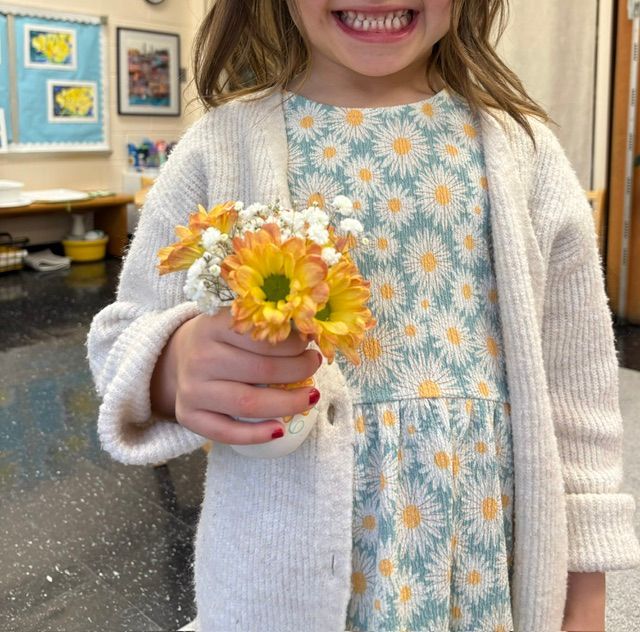 A little girl is holding a bouquet of flowers in her hand