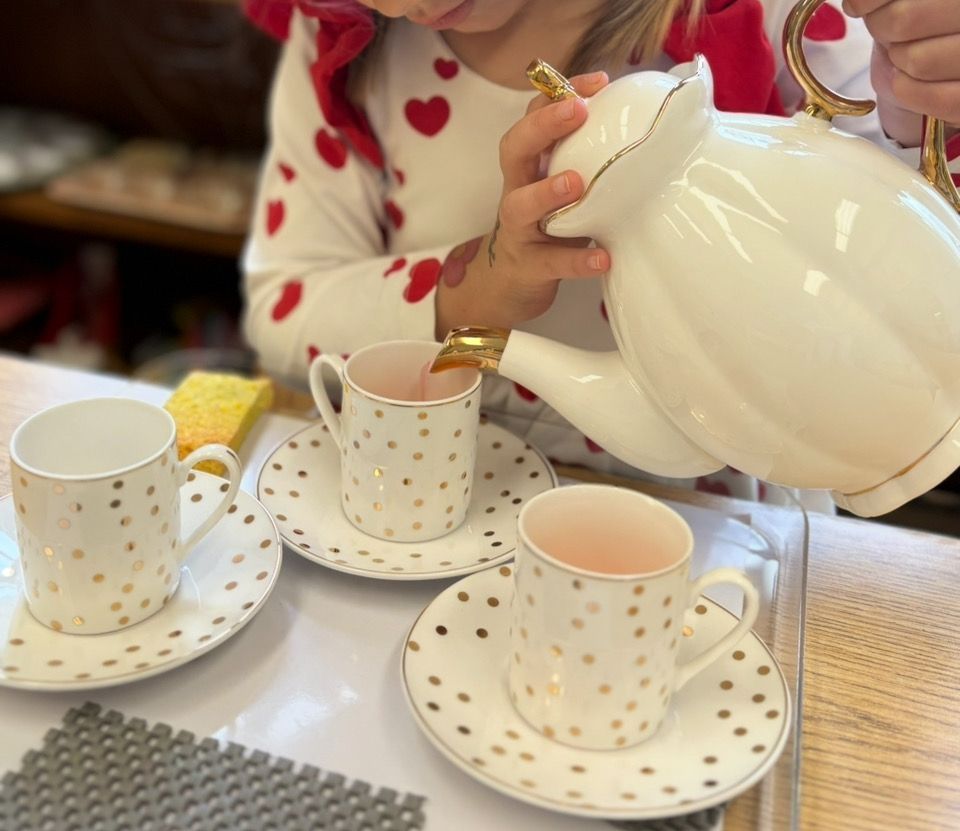 A little girl is pouring tea into three cups