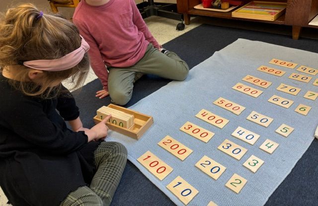 Two children are sitting on the floor playing with numbers