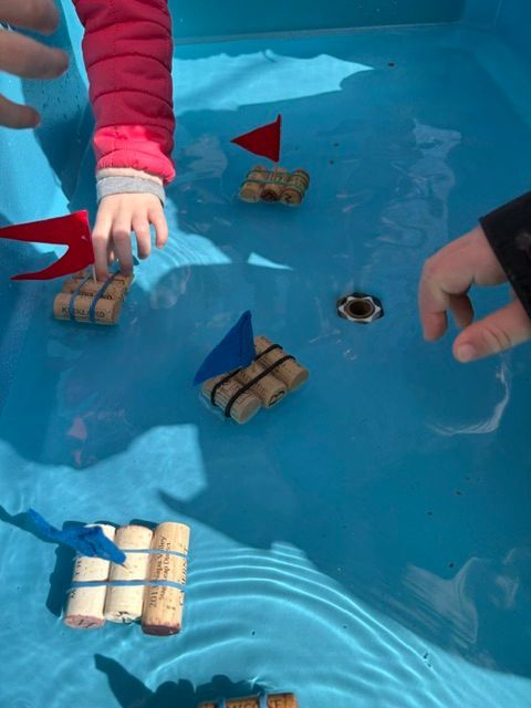 A child is playing with rafts made out of corks in a pool