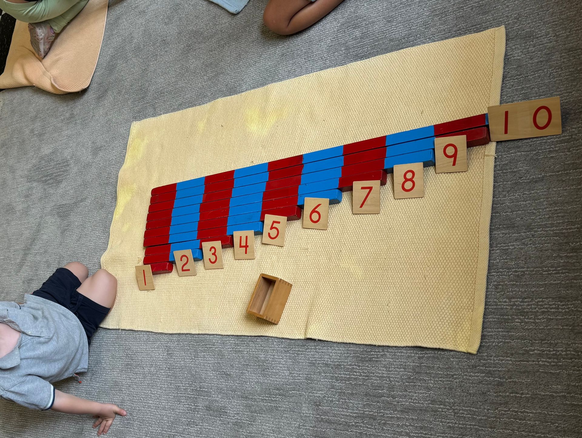 A child is laying on the floor playing with numbers on a mat.