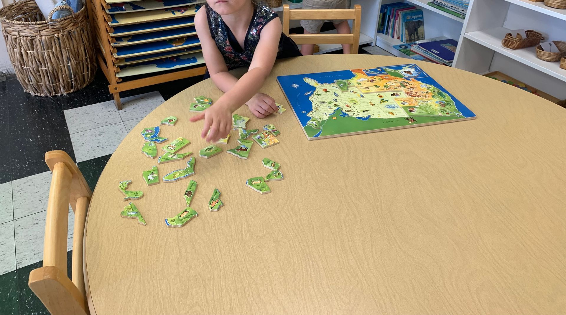 A little girl is sitting at a table playing with a puzzle.