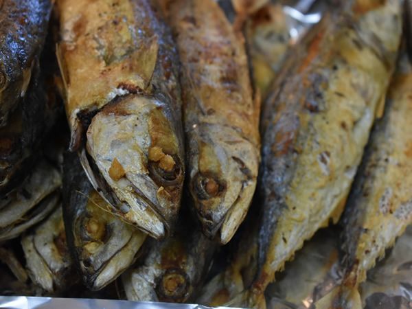 Fried fish, close-up. Golden-brown skin, visible scales, eyes closed.