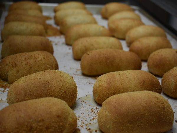Rows of golden, baked pan de sal rolls on a baking sheet.