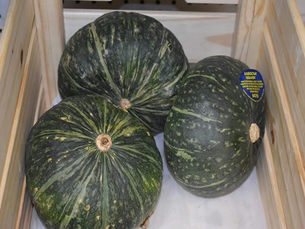 Three green kabocha squash in a wooden crate.