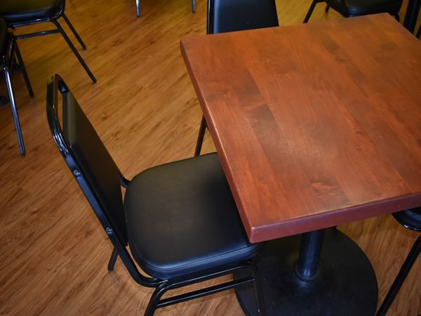Black chair at a small square wooden table on wood-grain flooring.