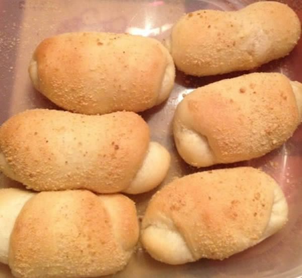 Six pan de sal rolls in a container, golden brown with a breadcrumb coating.