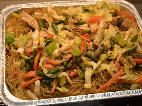 Pan of Filipino pancit bihon noodles with vegetables and meat.