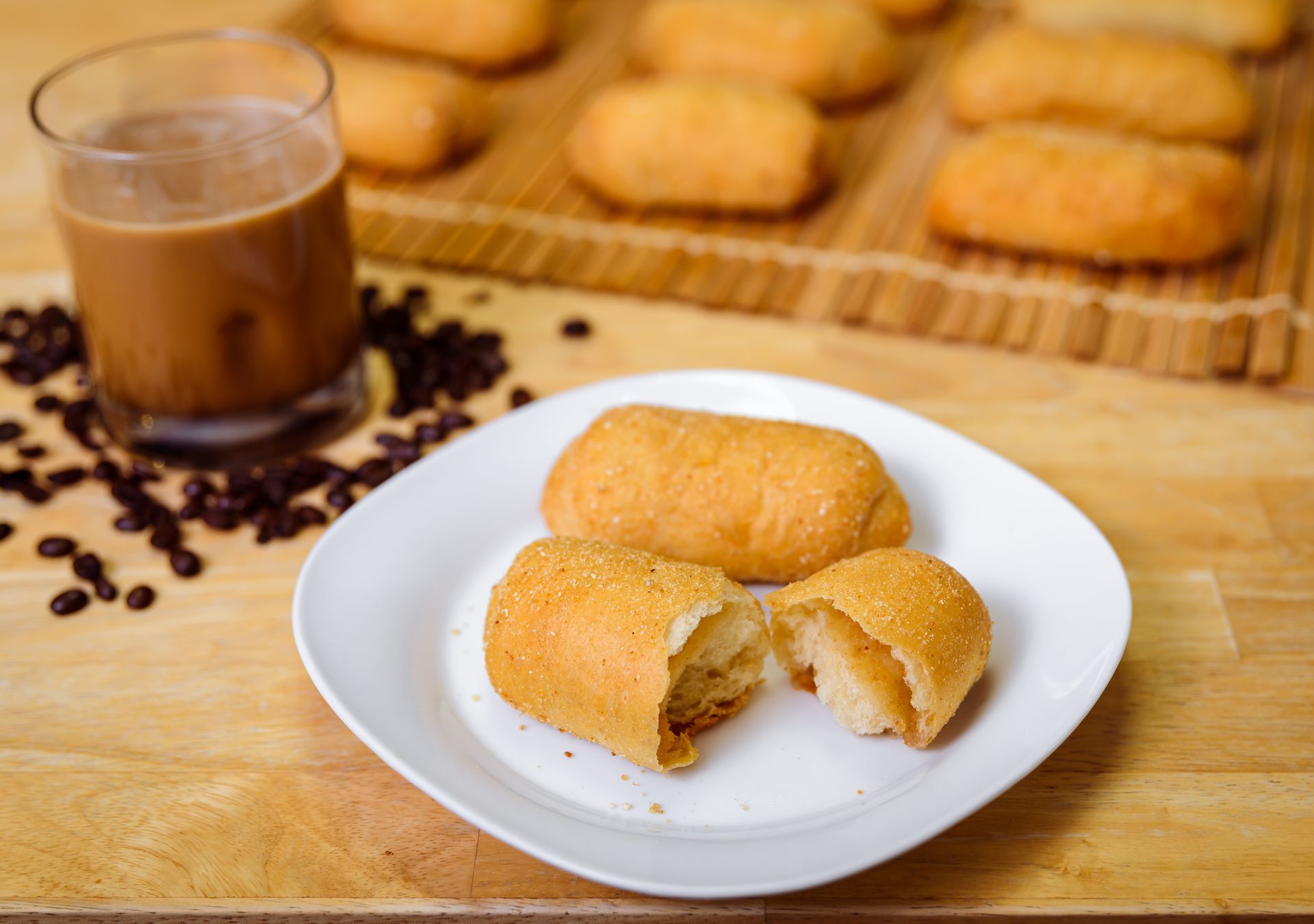 Fried pastries with coffee, beans scattered on wooden surface.