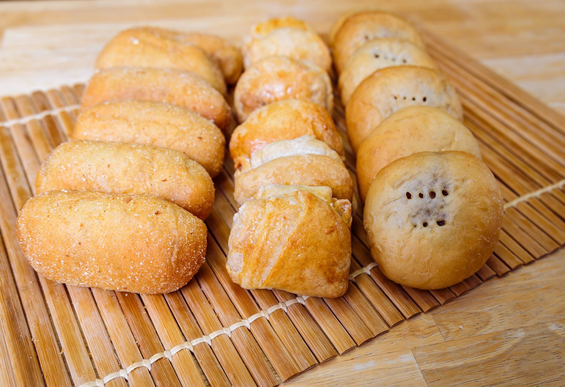 Assorted golden-brown pastries arranged on a bamboo mat.