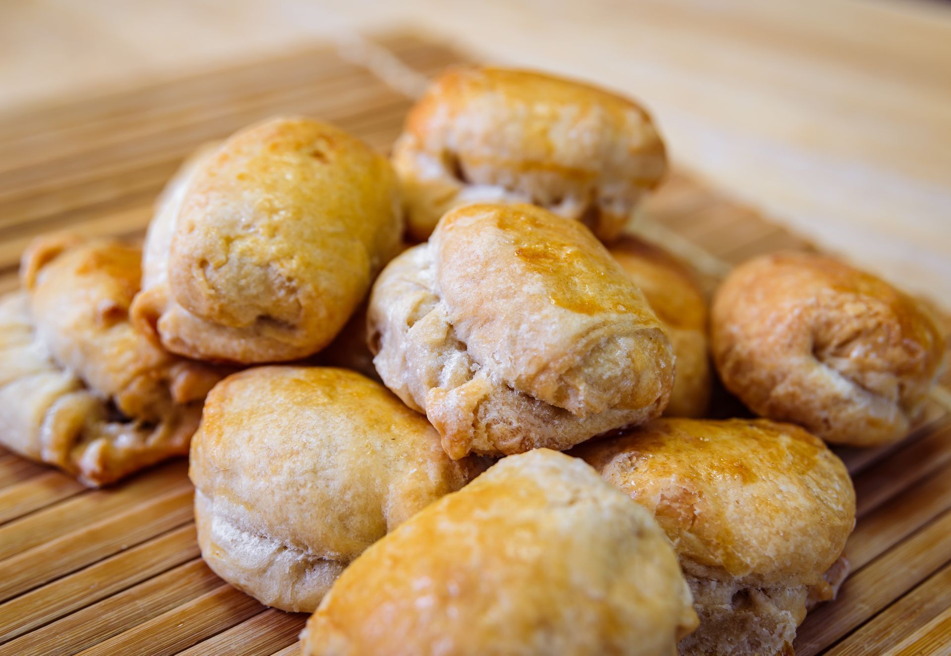 Pile of golden-brown pastries on a bamboo mat.