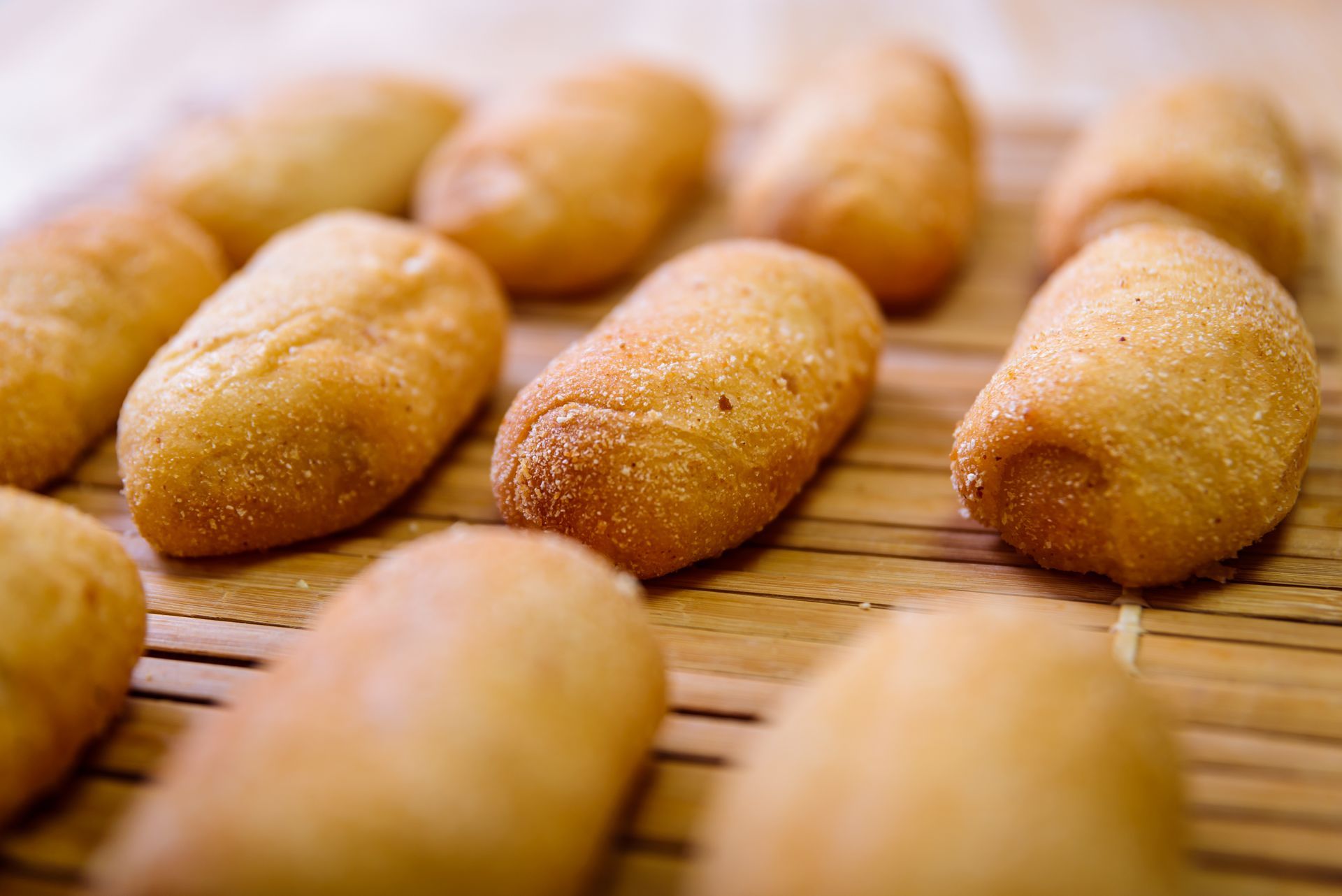 Golden brown, fried, oblong pastries on a bamboo surface.