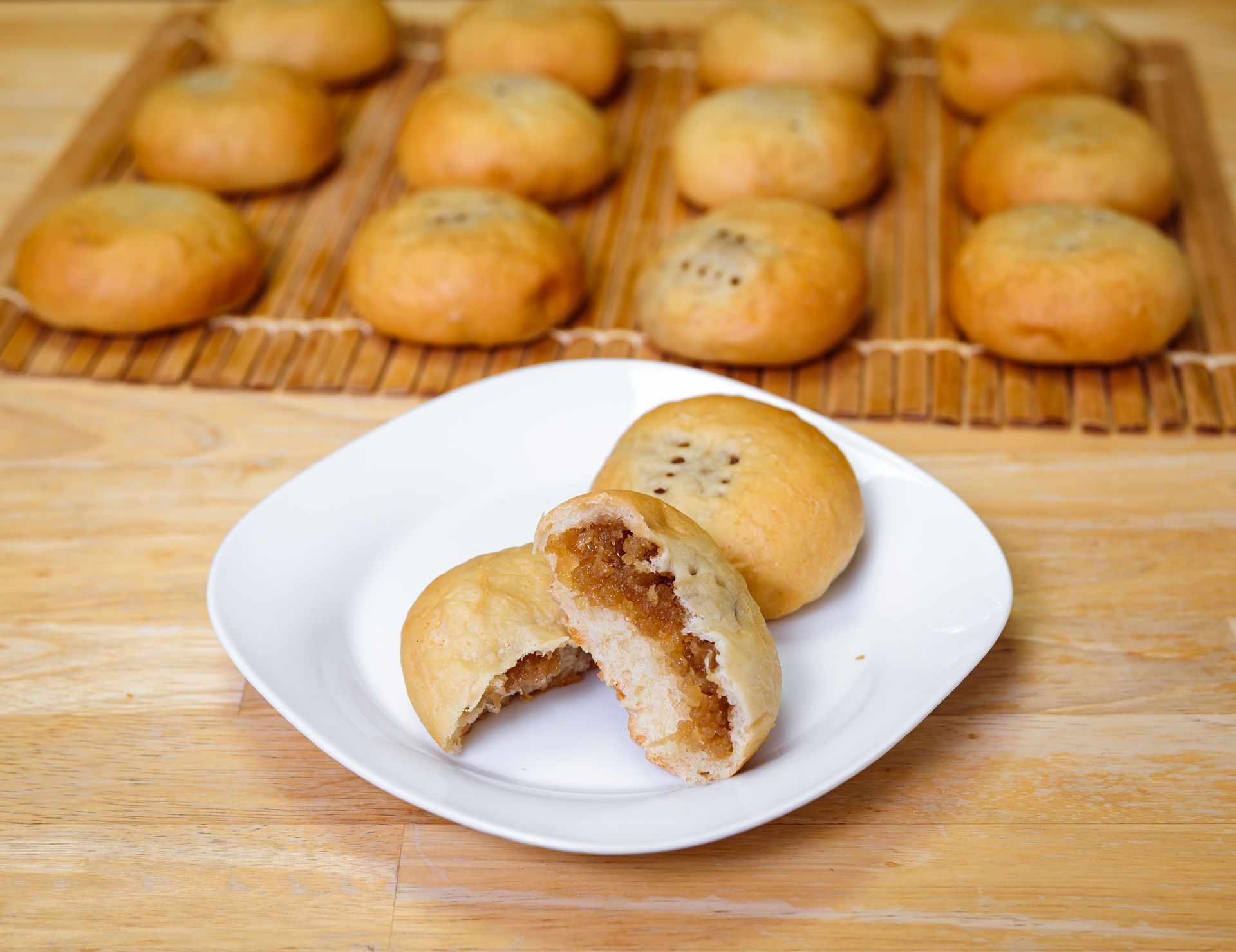 Plate of baked goods, one cut open to show filling; others rest on a mat in the background.