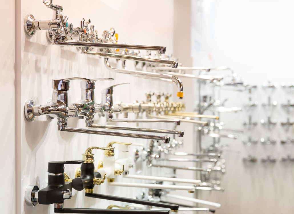 A display board in a showroom featuring various rows of chrome and black-and-white metal sink and shower faucets.
