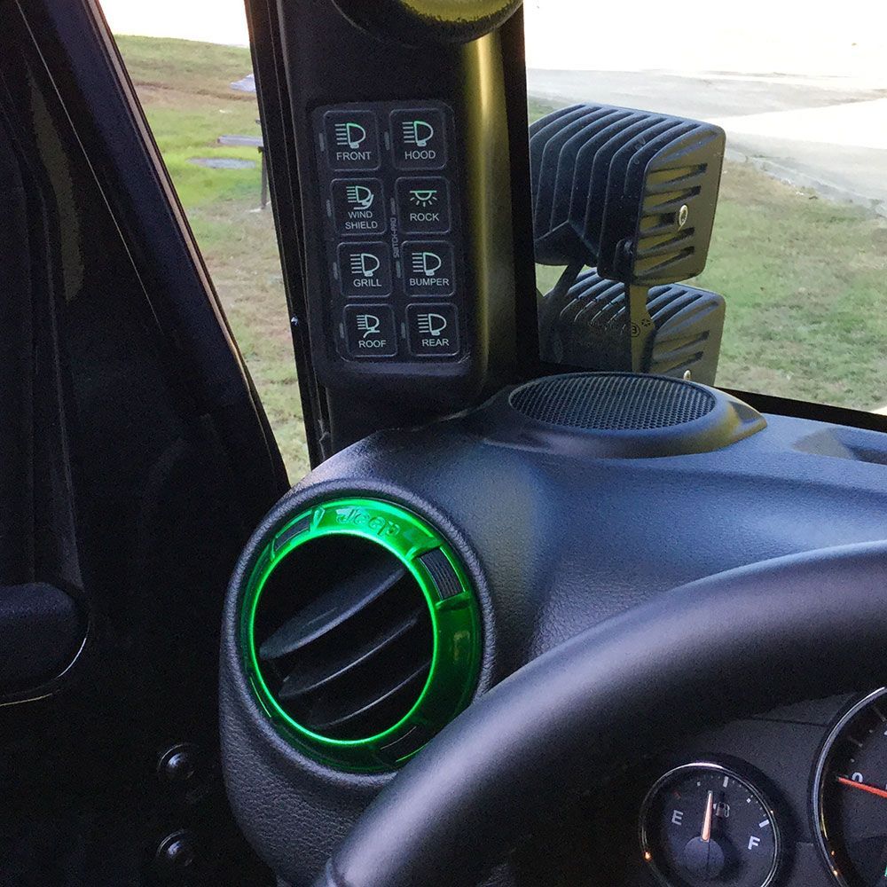 Black Jeep interior with light switches, green trim, and off-road lights.