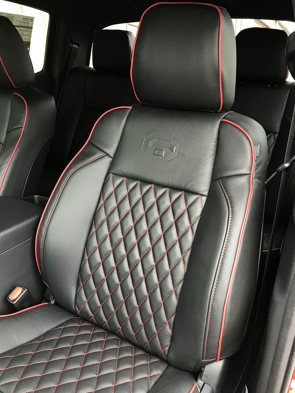 Black car seat with red stitching, diamond pattern on the bottom, red piping around the edges.