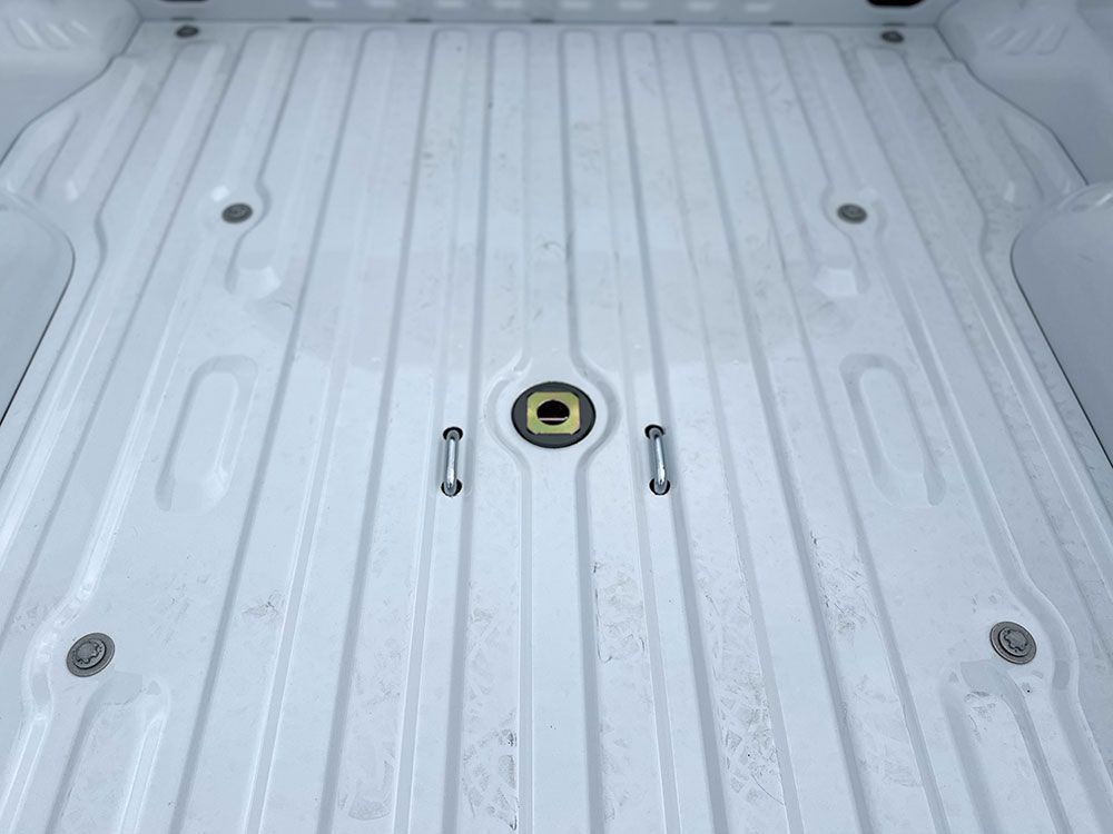 White truck bed with central gooseneck hitch and surrounding anchor points.