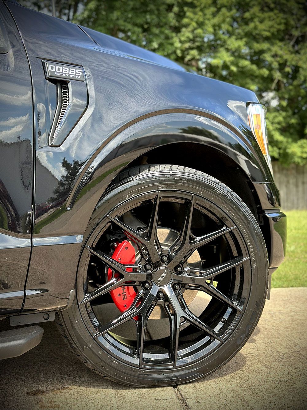 Black Ford F-150 with glossy black wheels, red brake calipers, and a black body.