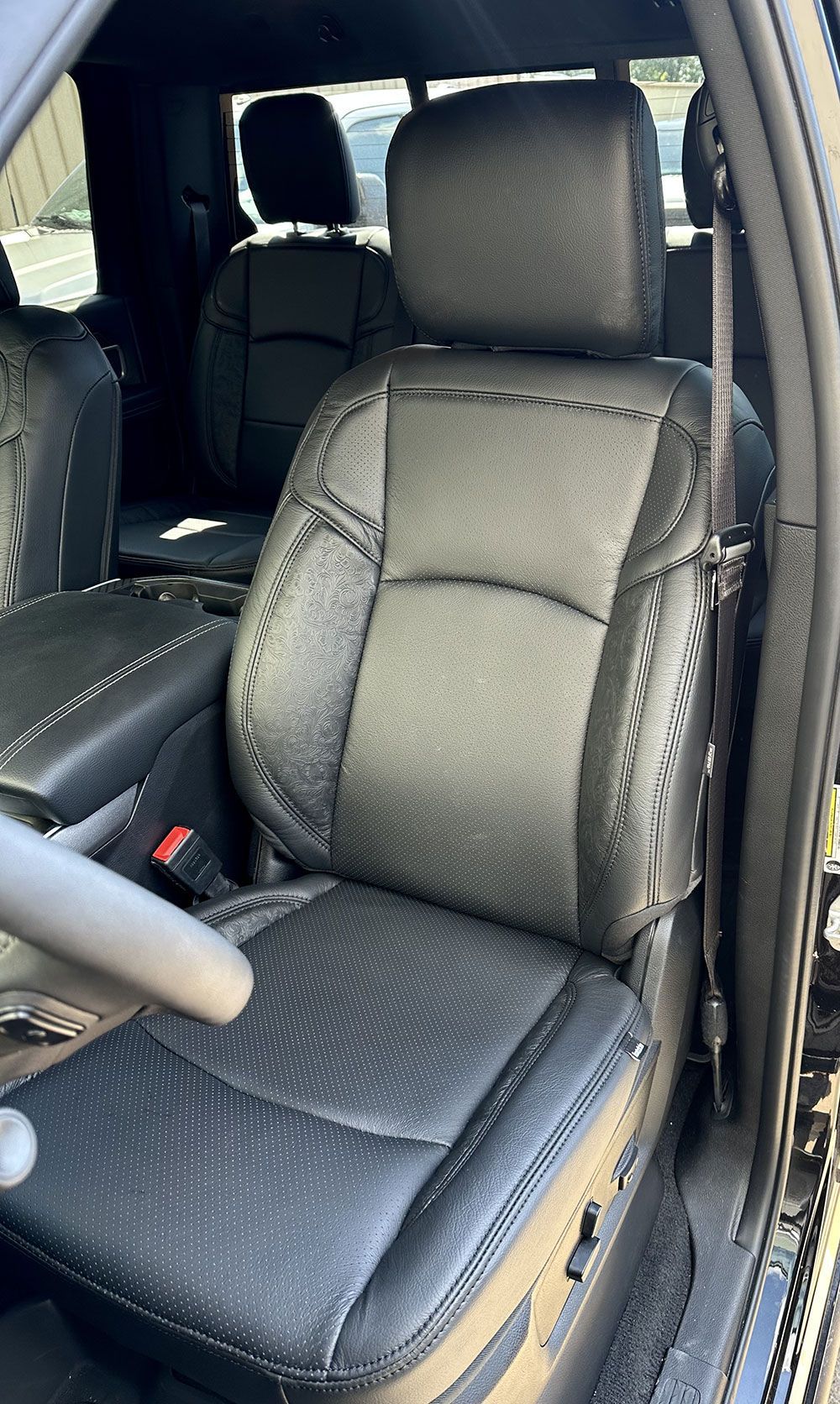 Black leather truck seat with stitching, seatbelt visible, interior.