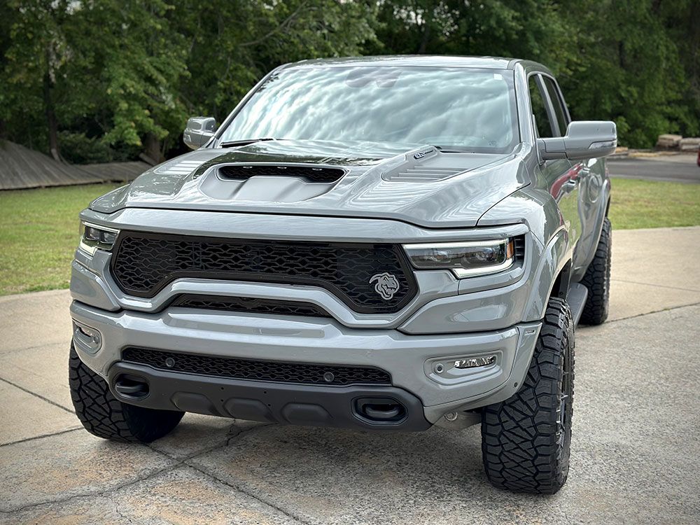 Gray Ram TRX truck parked outside with a black grill and large tires.