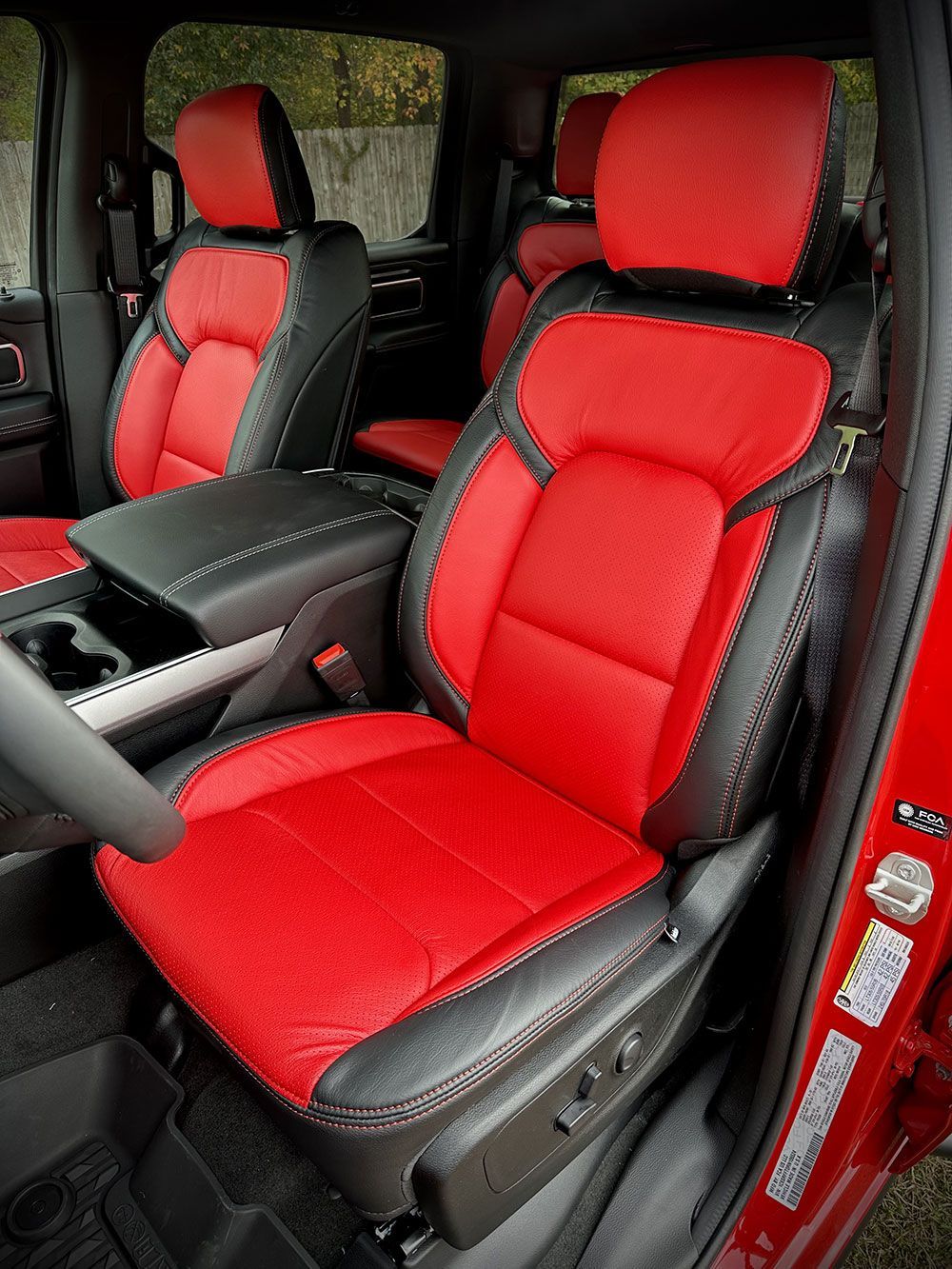 Red and black leather car seats inside a vehicle; seats have stitched details.