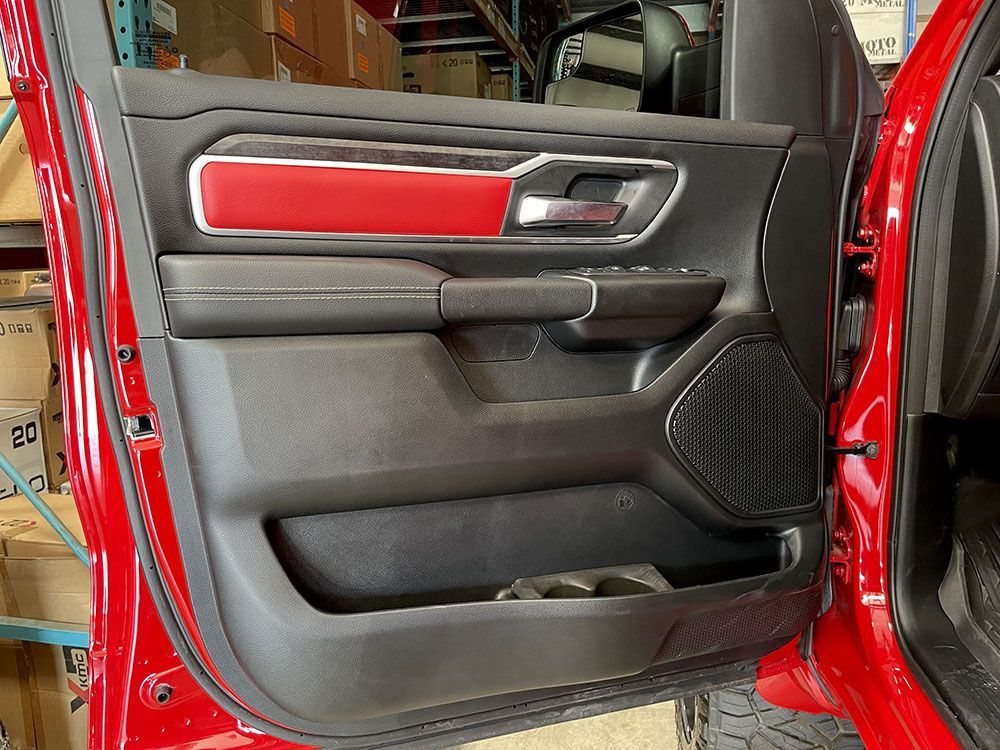 Red car door interior with black and red accents, speaker, and cup holder.