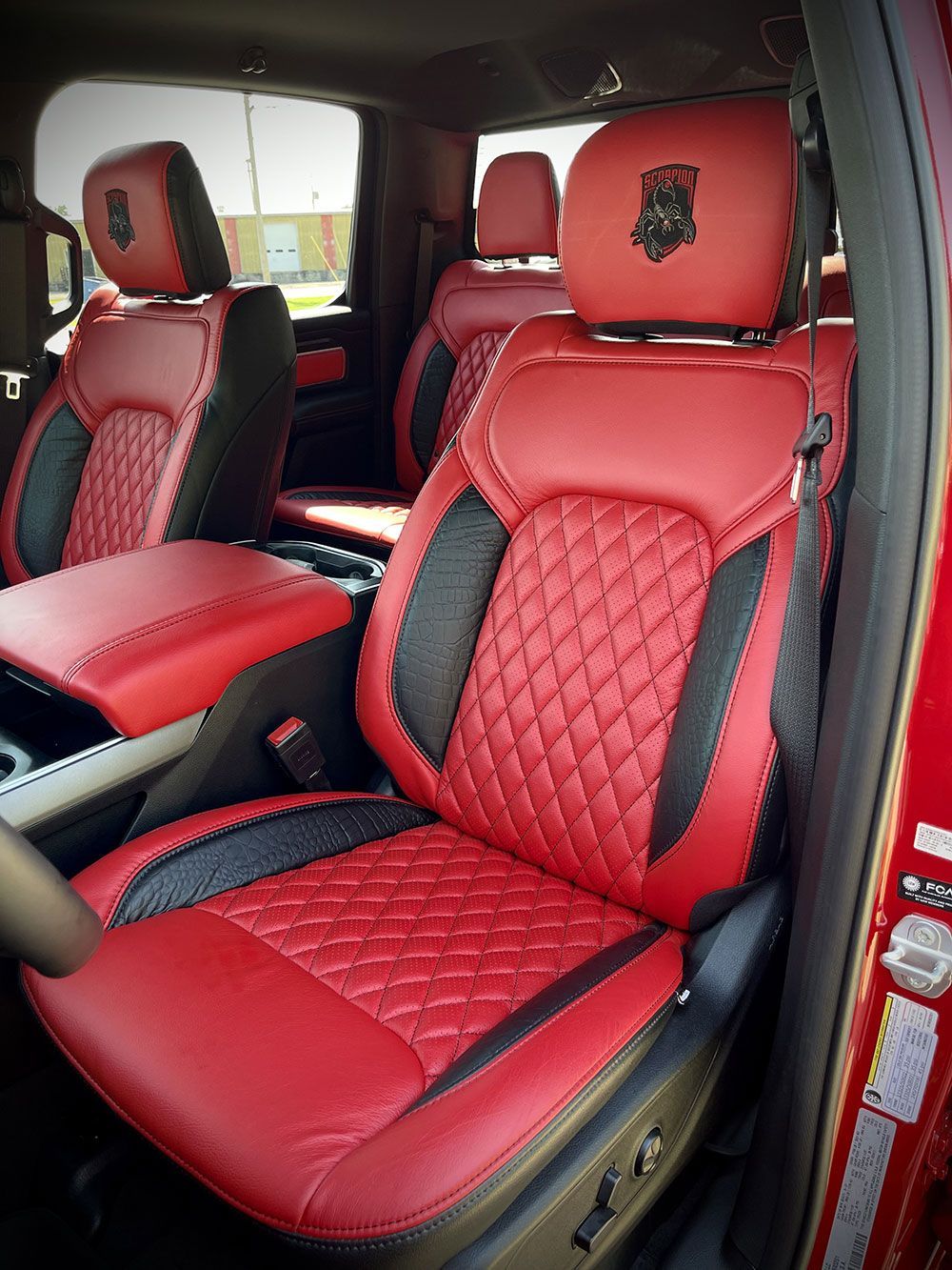 Red and black leather car seats with diamond stitching, logo on headrests.