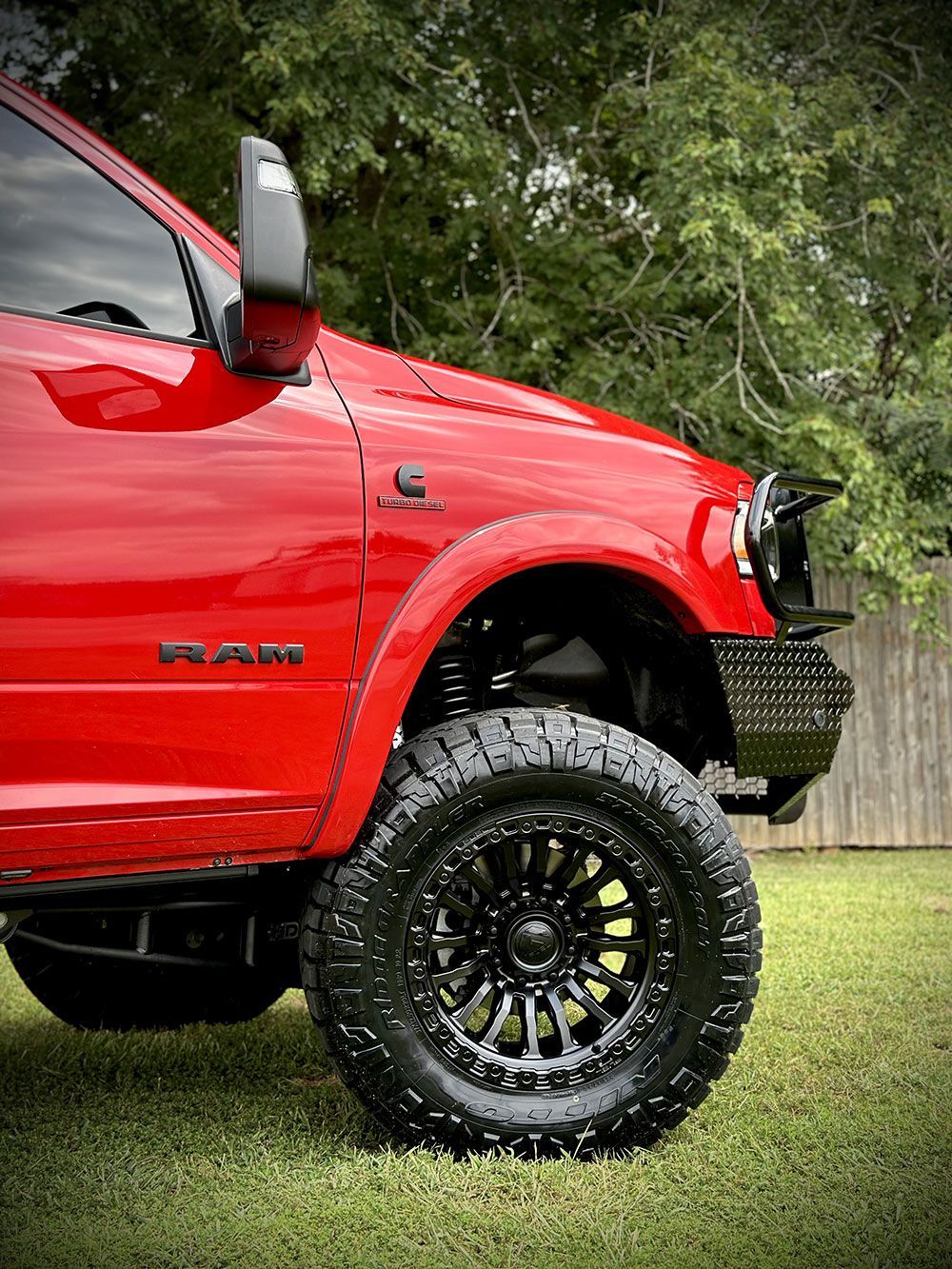 Red Ram truck with black wheels and tires parked on grass.