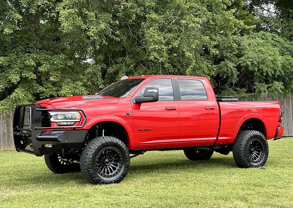 Red lifted pickup truck parked on grass.