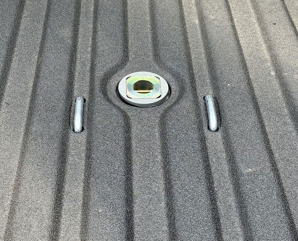 Truck bed with a gooseneck hitch and two mounting pins. Dark textured surface.
