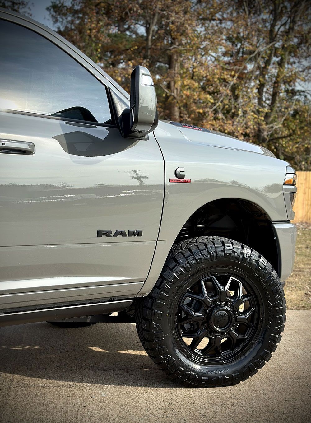 Gray pickup truck with black wheels parked on a road.