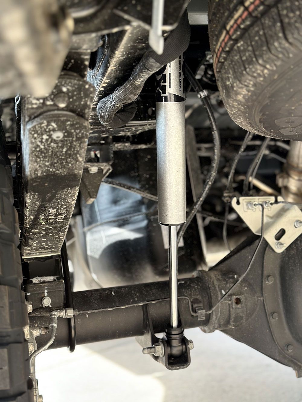 Undercarriage view of a truck suspension with a silver shock absorber mounted to the axle and frame.