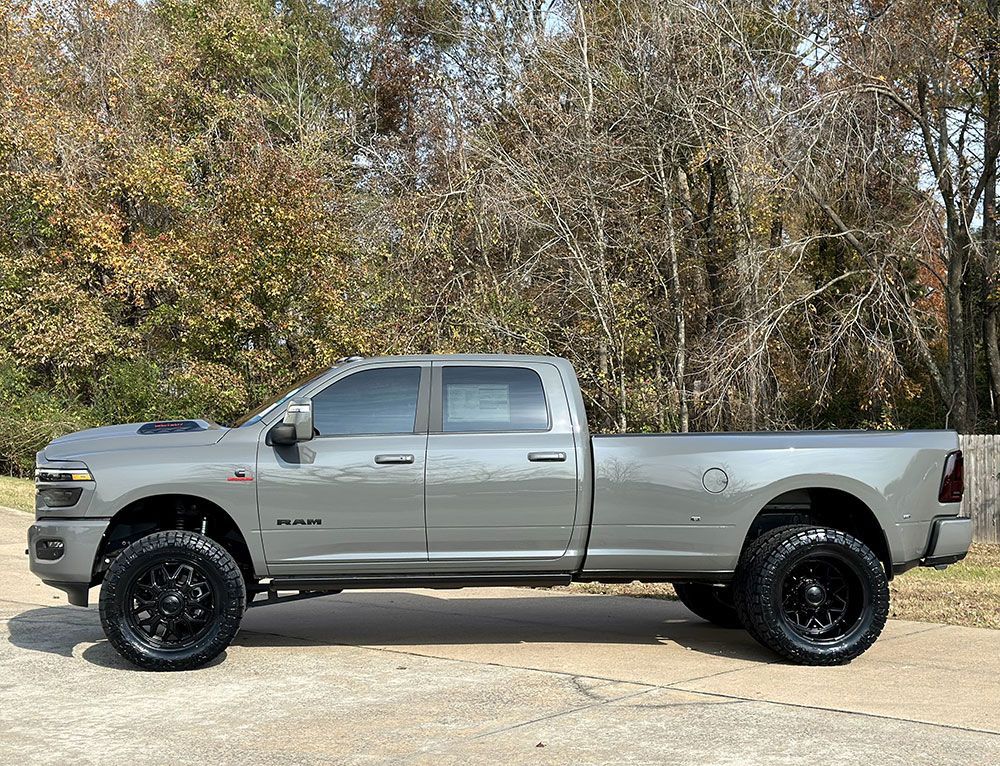 Gray RAM truck with large black wheels parked outside.