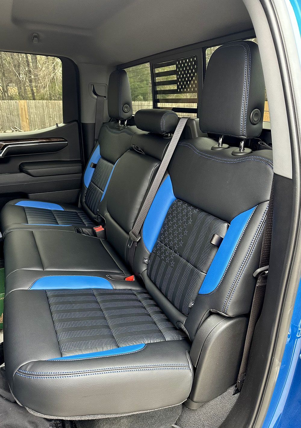 Blue and black leather truck backseat with a flag in the back window.