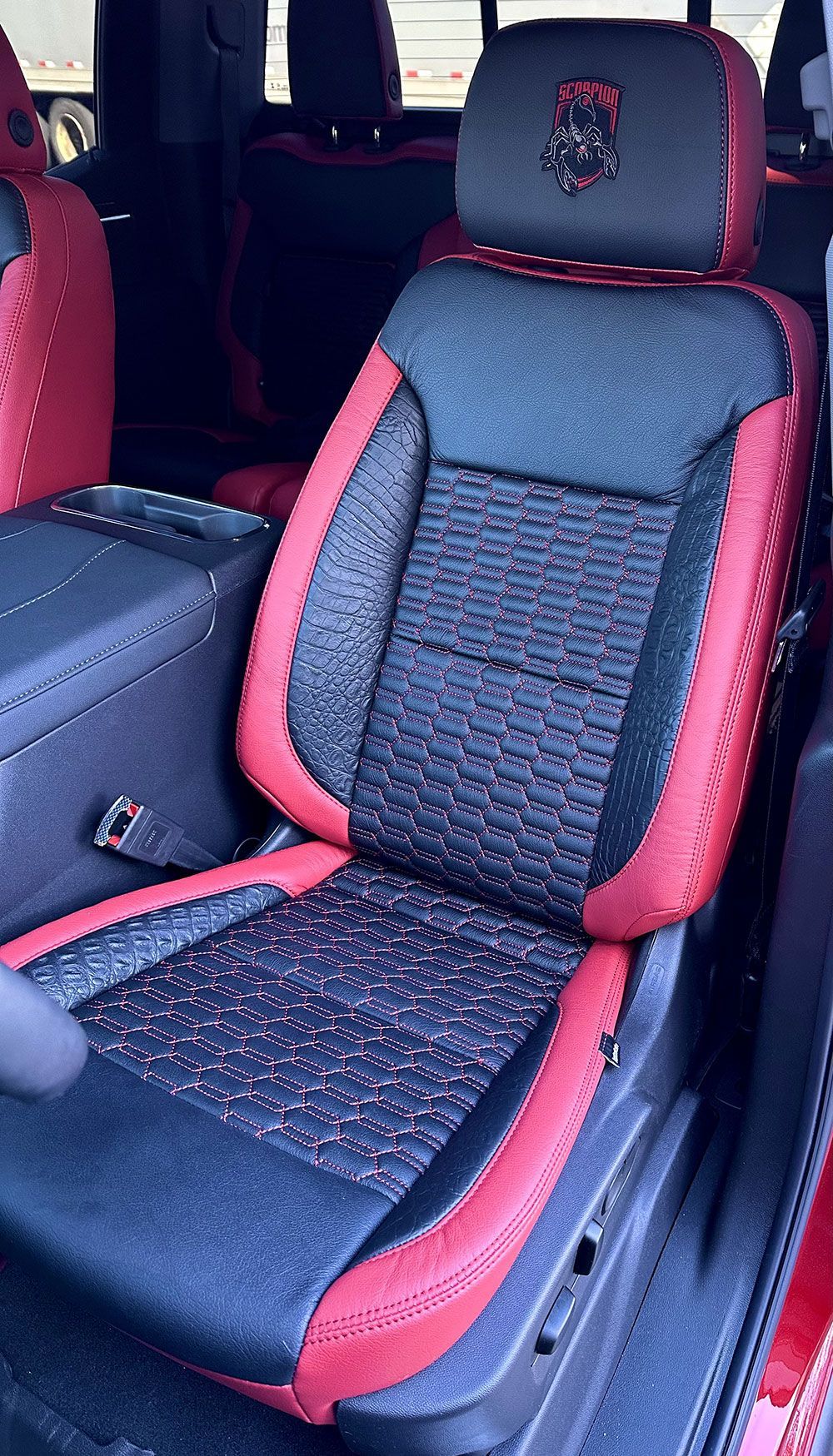 Red and black car seat with Ram logo on headrest.
