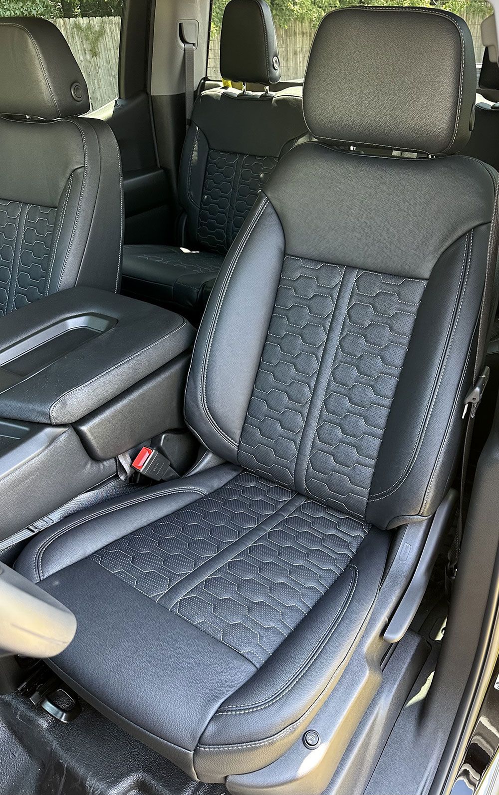 Black leather car seats with textured stitching and a center console.