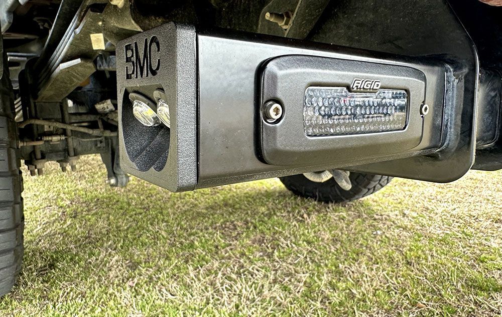 Black truck hitch with a light, BMC logo, and rear axle.