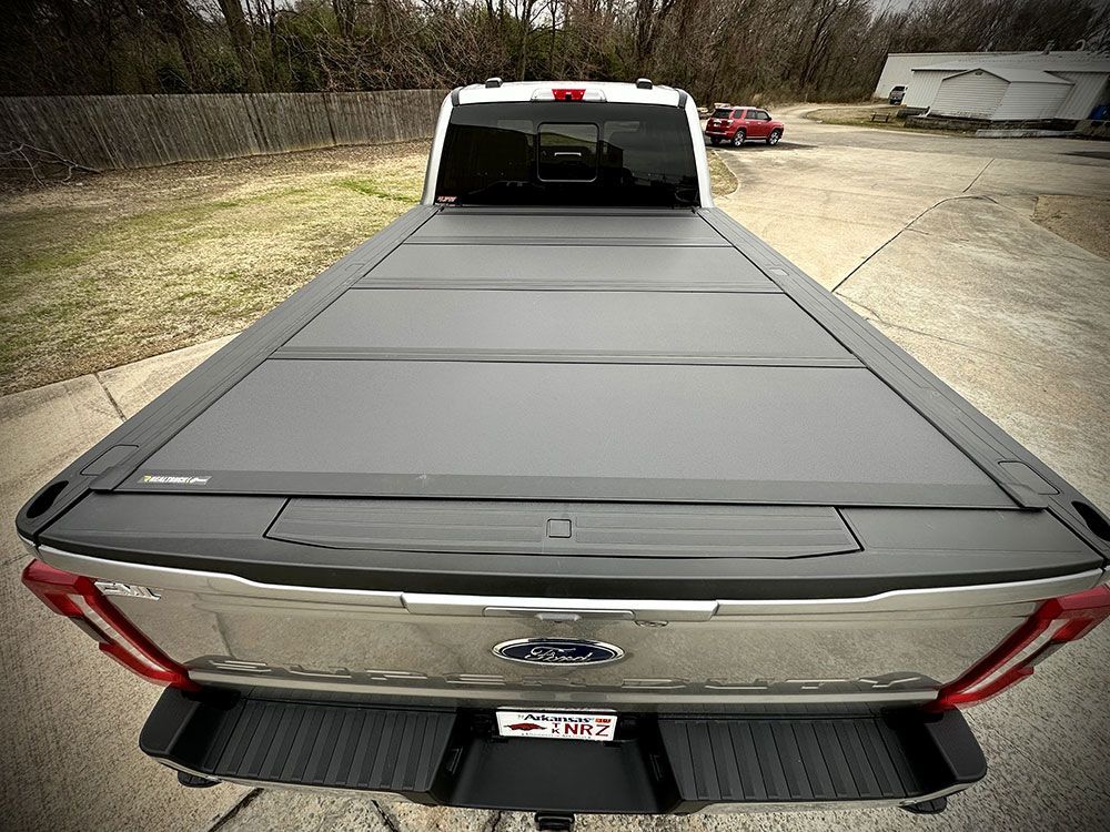 Silver Ford pickup truck with a black folding bed cover.
