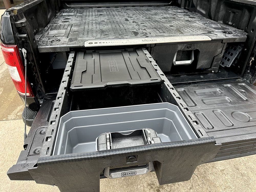Black truck bed with pull-out storage drawers and organizers, including a container with a winch.