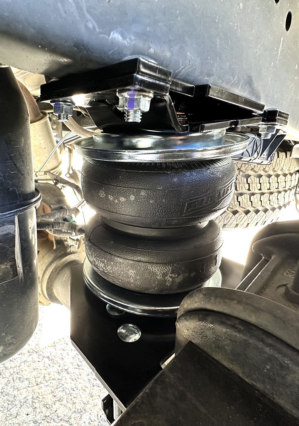 Air suspension system installed on a truck; black components, bolts, and an air bag.
